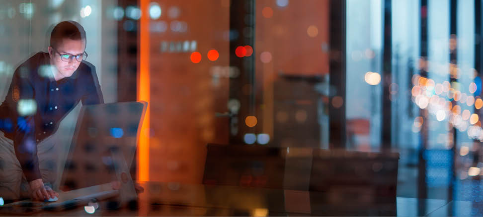Young man looking at computer in office at night